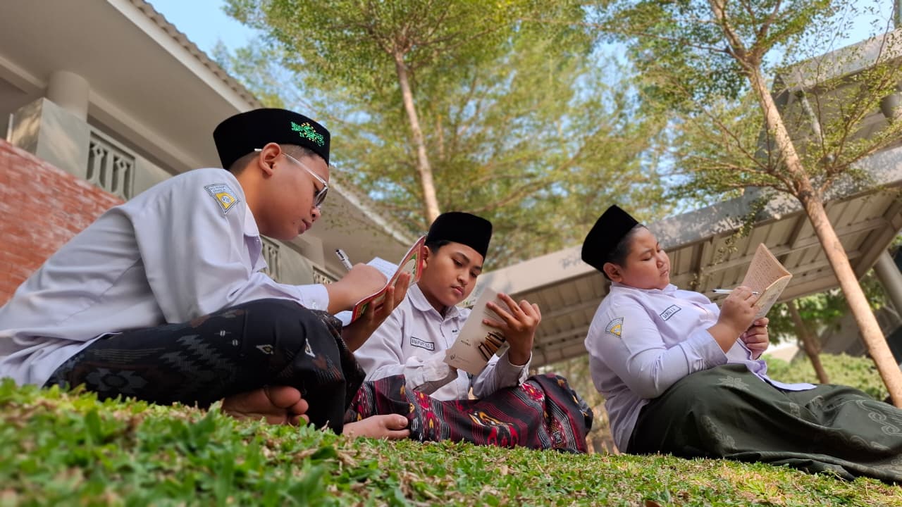 Santri membaca kitab di halaman madrasah